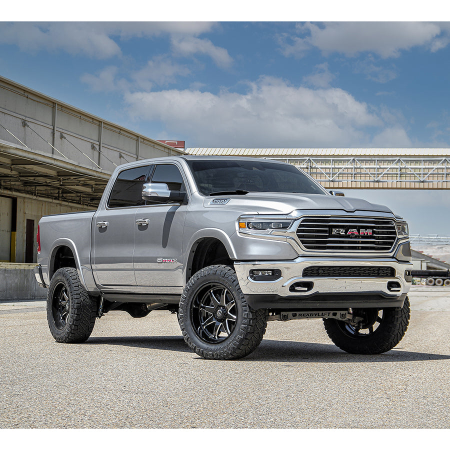 ReadyLIFT Lift Kit installed on a Ram 1500 Limited: silver Ram 1500 Limited crew cab lifted on black wheels and mud tires at an industrial yard