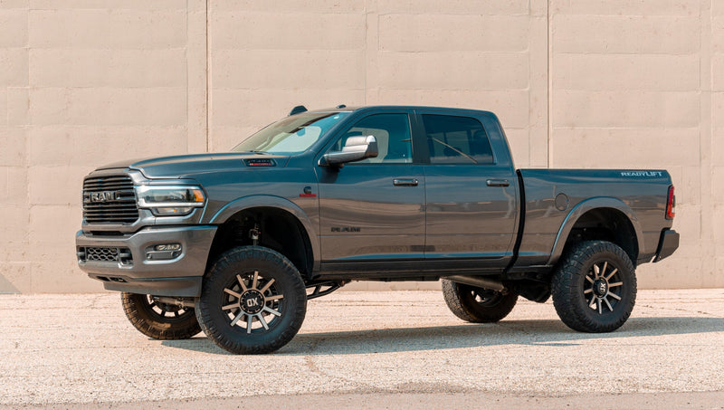 ReadyLIFT MAX3.3 Suspension System installed on a Ram 2500: blue-gray Ram 2500 crew cab lifted on bronze wheels in front of a concrete wall