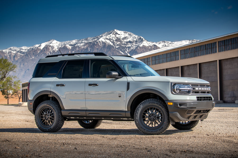 ReadyLIFT SST Lift Kit installed on a Ford Bronco Sport: A gray lifted Ford Bronco Sport parked on gravel in front of hangars with snowy mountains behind