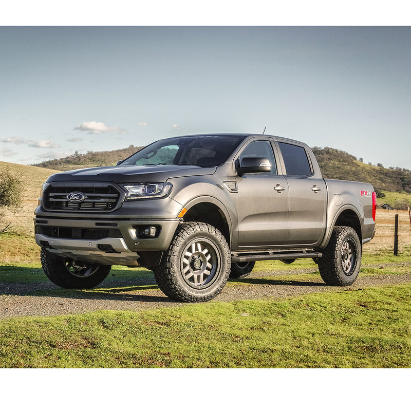 ReadyLIFT SST Lift Kit installed on a Ford Ranger: A gray lifted Ford Ranger SuperCrew parked on grass with hills behind