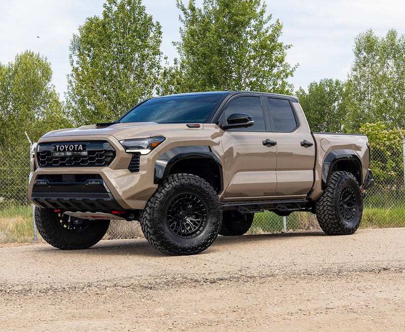 ReadyLIFT SST Lift Kit installed on a Toyota Tacoma: A tan lifted Toyota Tacoma TRD Pro Double Cab parked on gravel with trees behind