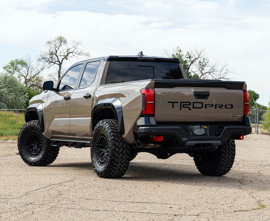 ReadyLIFT SST Lift Kit installed on a Toyota Tacoma: A tan lifted Toyota Tacoma TRD Pro seen from the rear three-quarter with TRD PRO on the tailgate