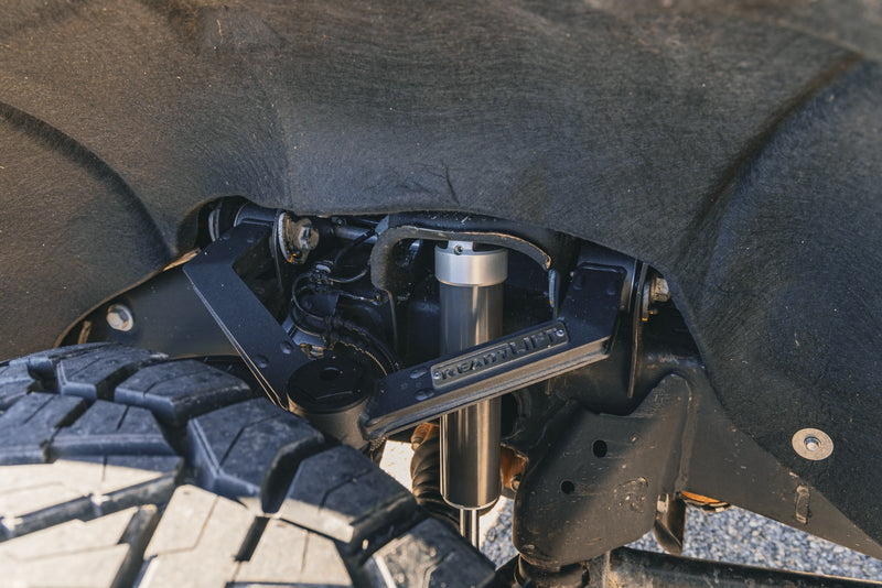 ReadyLIFT SST Lift Kit on a vehicle: close-up of an installed fabricated upper control arm and Falcon shock in a truck wheel well