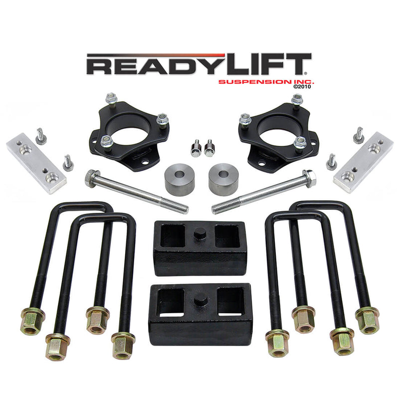 ReadyLIFT SST Lift Kit, full kit on a studio background: two black strut spacers, aluminum brackets, two 2" rear blocks and U-bolts under a ReadyLIFT logo