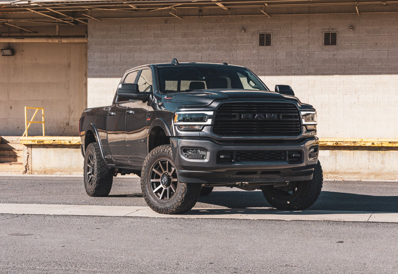 ReadyLIFT SST2.1 Coil Spring Lift Kit installed on a Ram 2500: A dark gray lifted Ram 2500 Crew Cab parked in front of a loading dock