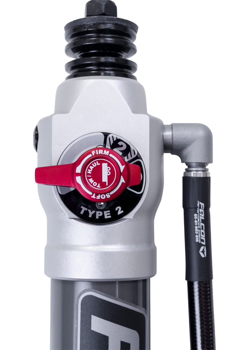 Close-up of the ReadyLIFT SST2.1 Suspension System: close-up of a silver Falcon shock body with a red Type 2 firm-soft adjuster knob on a black background