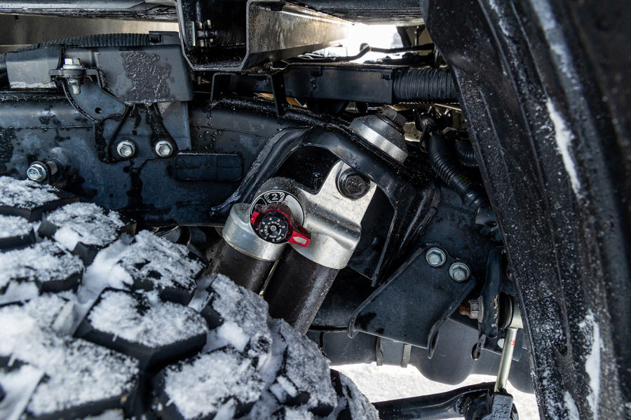 ReadyLIFT SST2.1 Suspension System on a vehicle: close-up of an installed Falcon rear shock with a remote reservoir beside a snowy tire