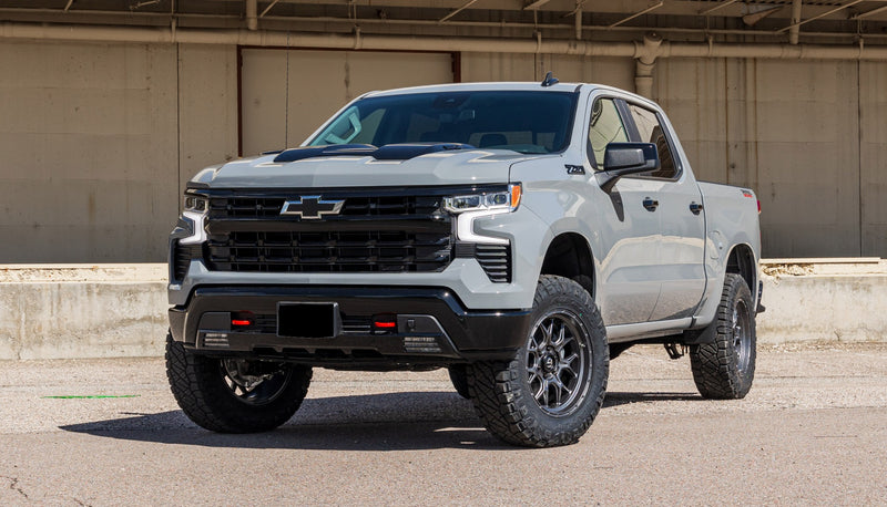 ReadyLIFT Suspension System installed on a Chevrolet Silverado 1500: A gray lifted Chevrolet Silverado 1500 Crew Cab parked by a loading dock