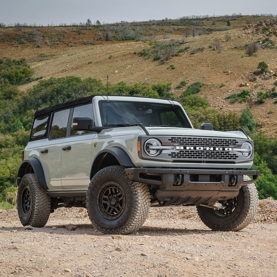 Leveling Kits by ReadyLIFT: Gray Ford Bronco four-door leveled on black wheels and all-terrain tires on a dirt hillside.