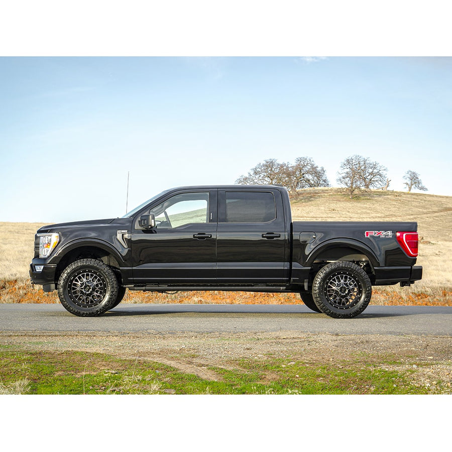 Leveling Kits by ReadyLIFT: Black Ford F-150 FX4 crew cab leveled on bronze wheels, side profile on a rural road.