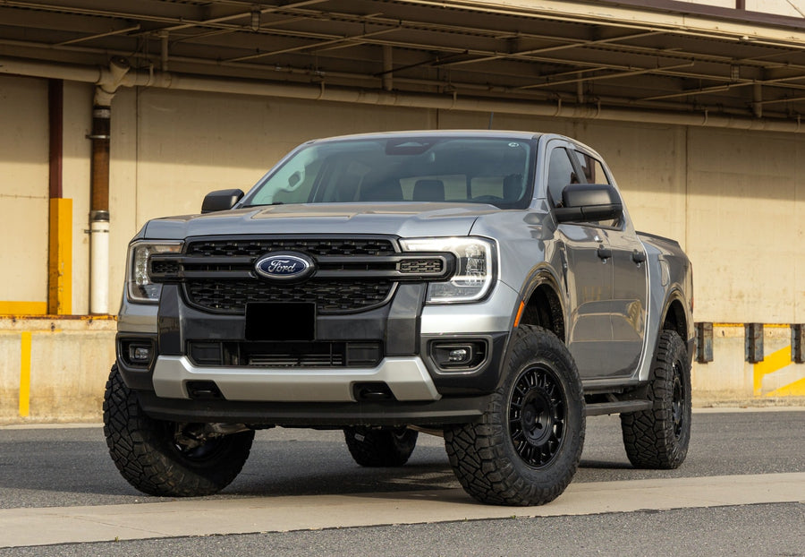Leveling Kits by ReadyLIFT: Gray fourth-generation Ford Ranger crew cab leveled on black wheels in front of a warehouse, plate blanked.