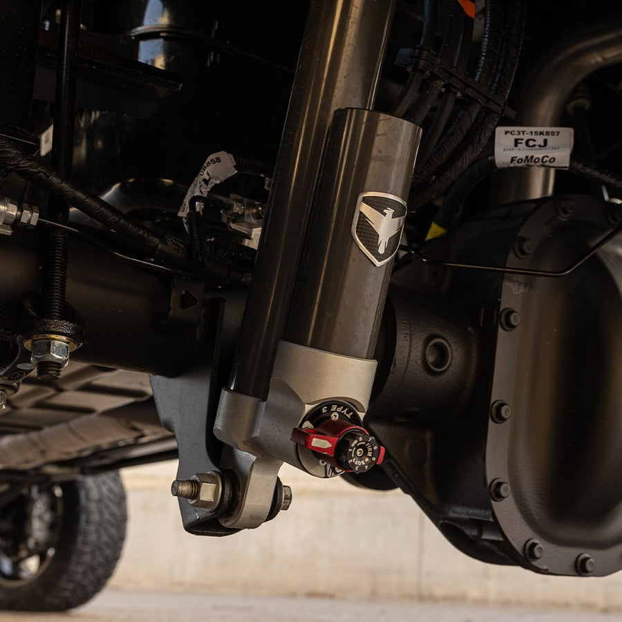 Performance Leveling Kits by ReadyLIFT: Falcon reservoir shock with red adjuster installed next to a heavy-duty rear axle, close view.