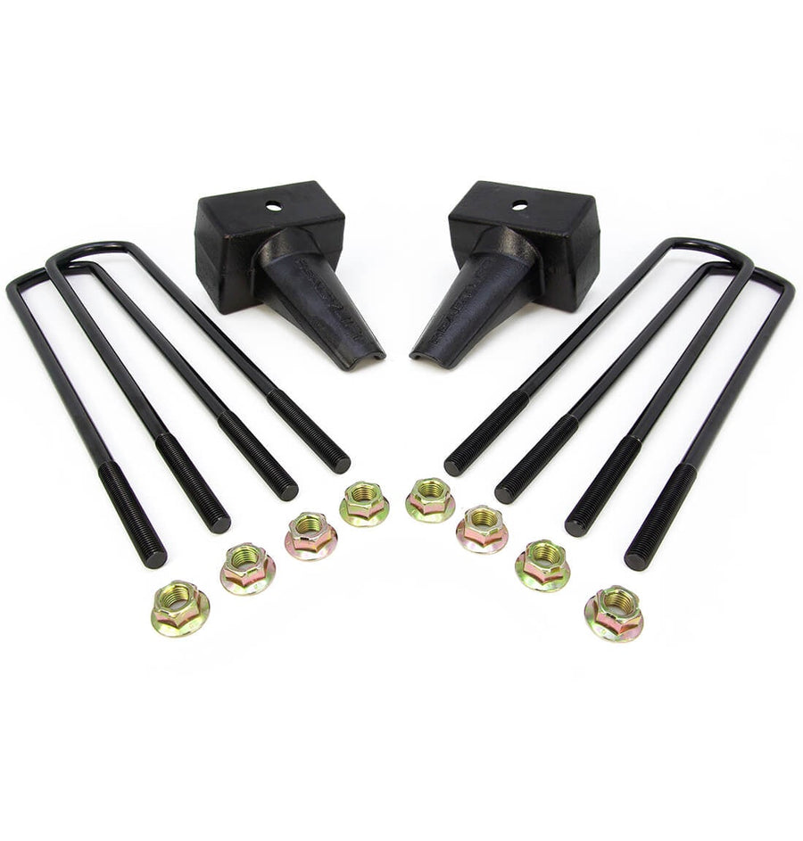 Rear Block Kits by ReadyLIFT: Two black tapered 4" rear lift blocks with four square black U-bolts and gold nuts on white.