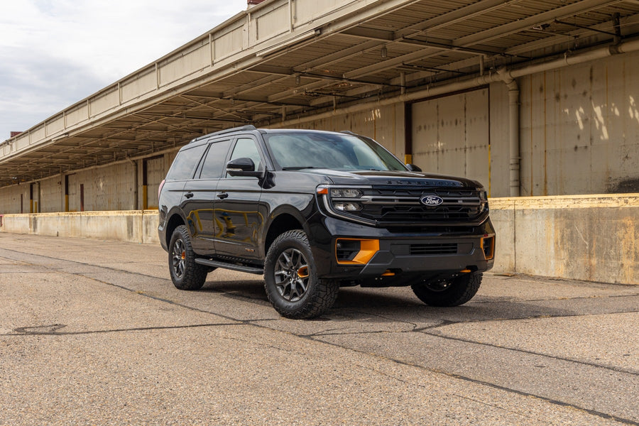 SST Lift Kits by ReadyLIFT: A black lifted Ford Expedition Tremor parked beside a long loading dock.
