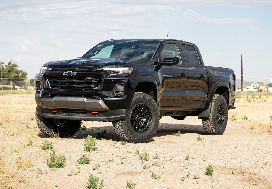 SST Lift Kits by ReadyLIFT: A black lifted Chevrolet Colorado Crew Cab parked on dirt with sparse grass.