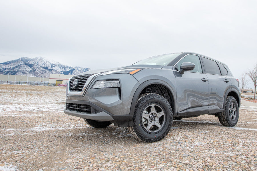 SST Lift Kits by ReadyLIFT: A gray lifted Nissan Rogue parked on a snowy gravel lot with mountains behind.