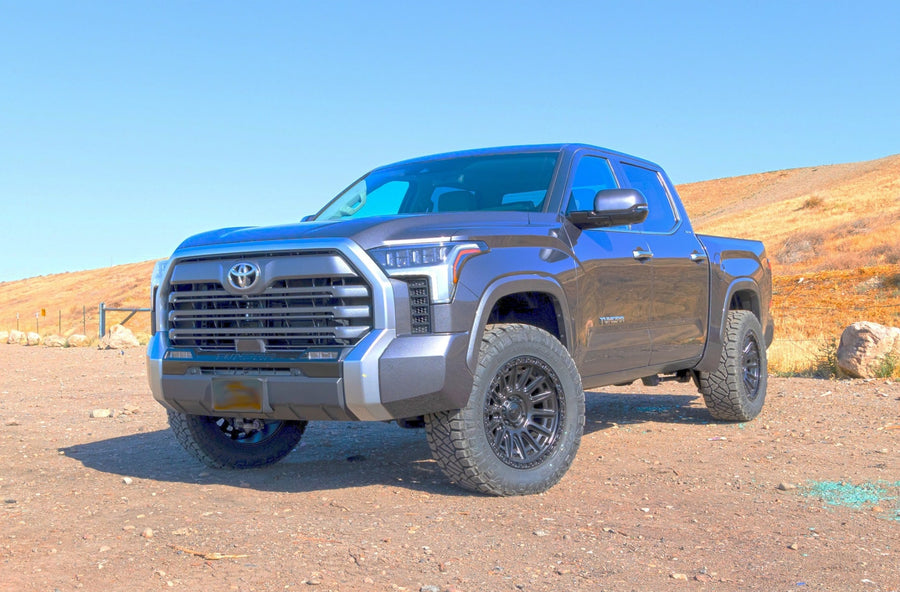 SST Lift Kits by ReadyLIFT: A gray lifted Toyota Tundra CrewMax parked on a dirt lot with dry hills behind.
