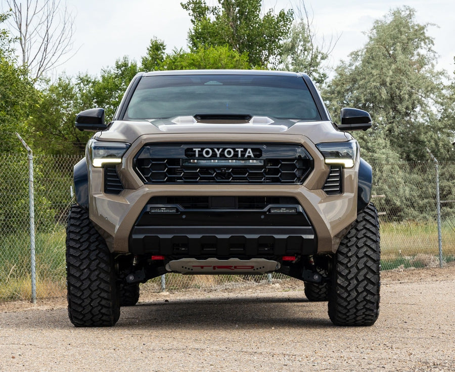 SST Lift Kits by ReadyLIFT: A tan lifted Toyota Tacoma TRD Pro seen head-on on a gravel lot.