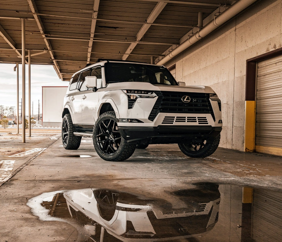 SST Lift Kits by ReadyLIFT: A white lifted Lexus GX550 parked under a loading dock canopy with its reflection in a puddle.