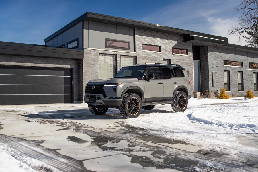 SST Lift Kits by ReadyLIFT: A gray lifted Lexus GX550 Overtrail parked on a snowy driveway in front of a modern house.