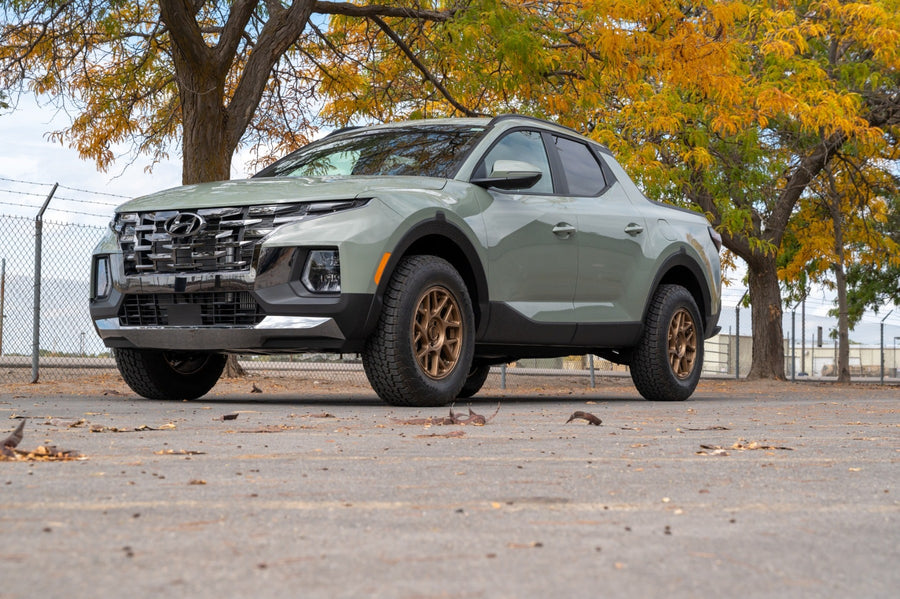 SST Lift Kits by ReadyLIFT: A sage green lifted Hyundai Santa Cruz on bronze wheels parked under autumn trees.