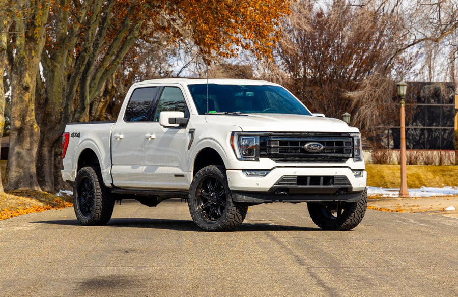 SST Performance Lift Kits by ReadyLIFT: A white lifted Ford F-150 SuperCrew parked on a road under autumn trees.