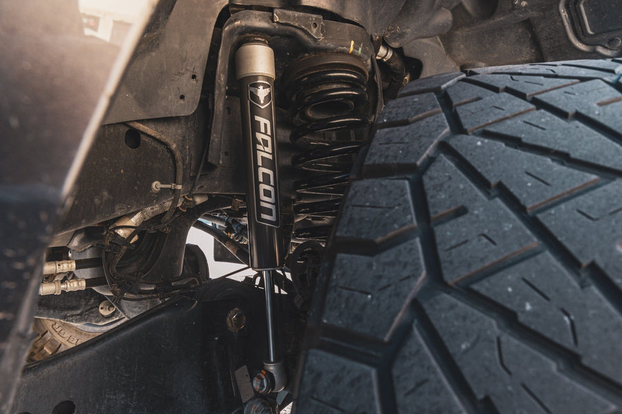 SST Performance Lift Kits by ReadyLIFT: Close-up of an installed Falcon front shock and coil spring behind a tire.