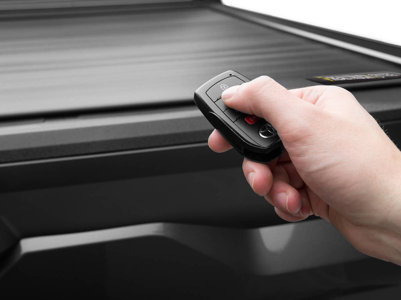 Hand pressing the truck key fob to operate the closed Retrax EQ cover