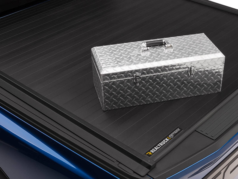 Close-up of the closed Retrax IX matte black aluminum slats with a diamond-plate toolbox resting on top