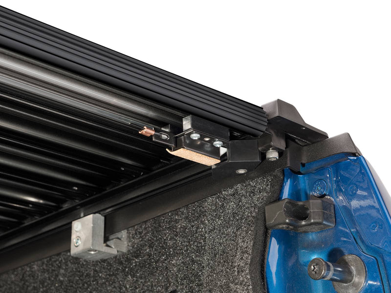 Retrax IX rail end and tailgate-side latch hardware with the slats retracted, viewed from the bed corner