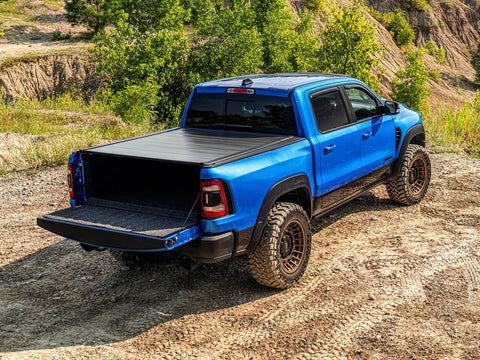 Retrax IX cover fully closed on a blue pickup with the tailgate down, outdoors on a dirt trail