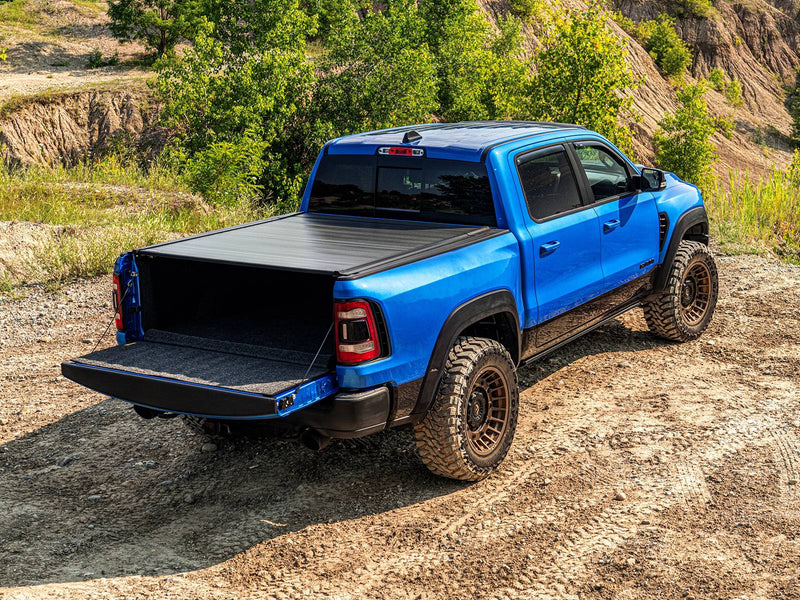 Retrax IX cover fully closed on a blue pickup with the tailgate down, outdoors on a dirt trail