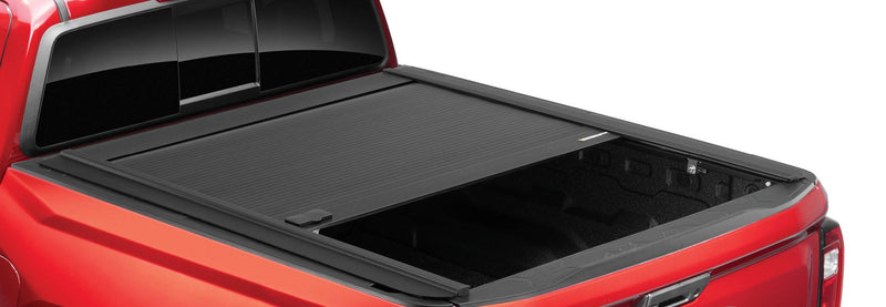 RetraxONE MX retractable cover part-open on a red pickup, slats rolled halfway toward the canister, latch lid visible