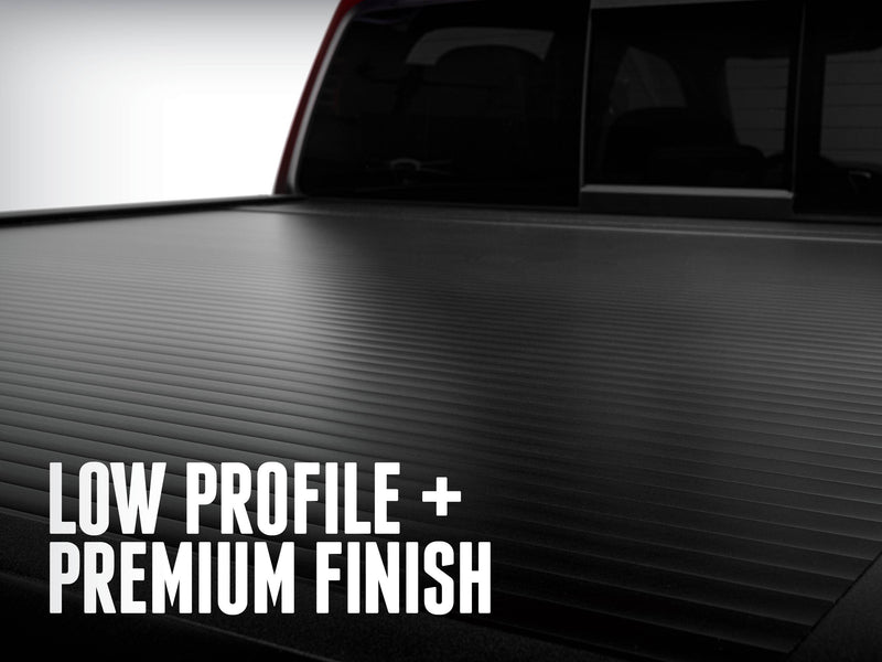 RetraxONE XR matte black slatted cover closed, low angle toward the cab; overlay headline about low profile and finish
