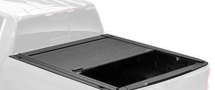 RetraxPRO MX retractable cover part-open in full color on a ghosted pickup, slats rolled halfway with the oval TraxLatch handle visible