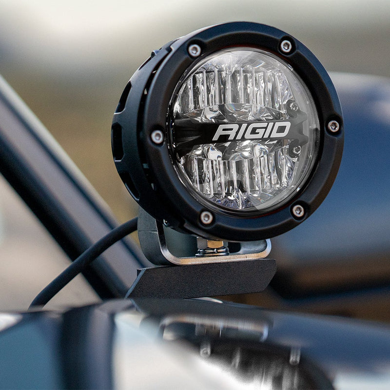Close-up of the Rigid 360-Series 4" Drive A-Pillar Light Kit: close-up of a black 4" 360-Series pod with a clear lens on an A-pillar mount