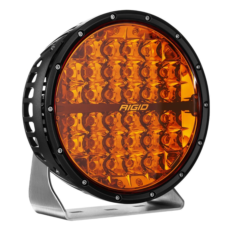 Rigid 360-Series PRO 9" on a studio background: A black 9" round LED light with an amber lens and polished bracket, angled against white
