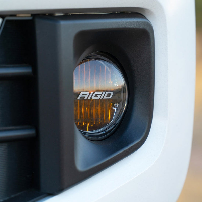 Rigid 360-Series yellow-lens round fog light fitted in the fog pocket of a white bumper
