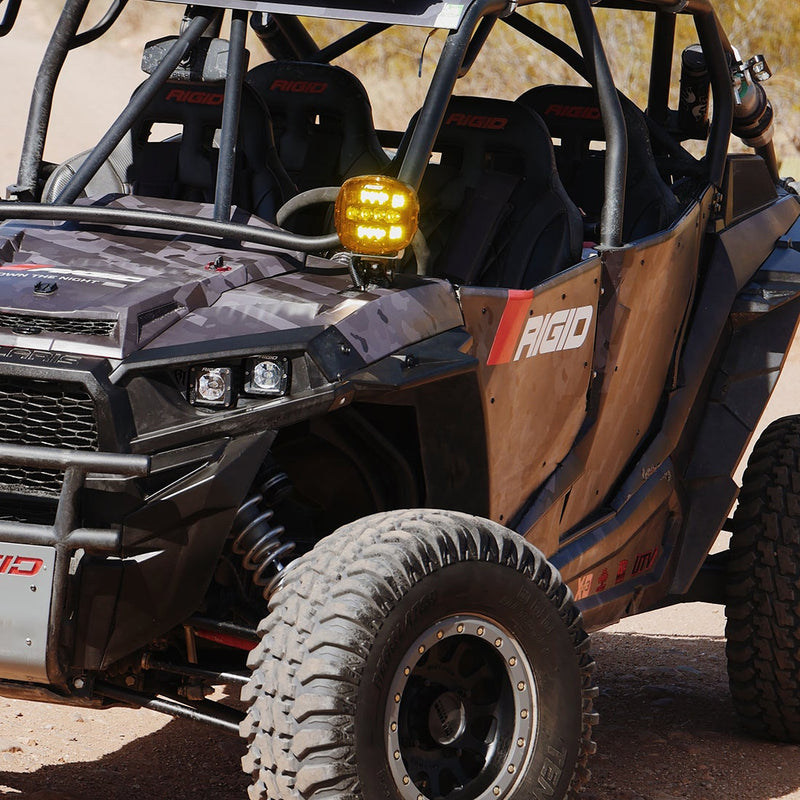 Rigid Adapt XP Cover installed on a Polaris RZR: A side by side with Rigid door panels carries a light with an amber cover mounted on its roll cage