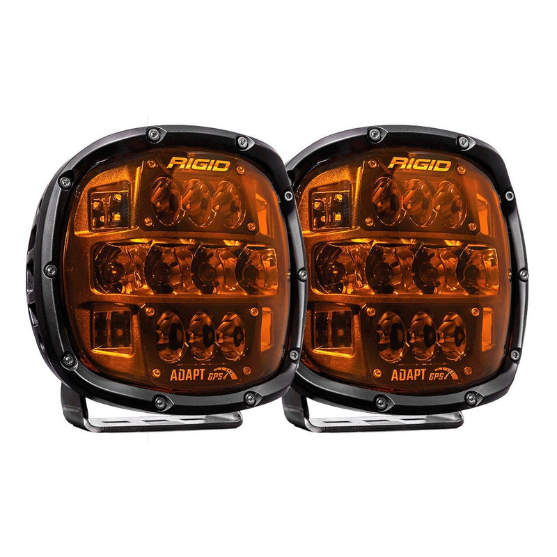 Rigid Adapt XP Pair on a studio background: two black Adapt XP LED lights with amber lenses on bail mounts, viewed straight on against white