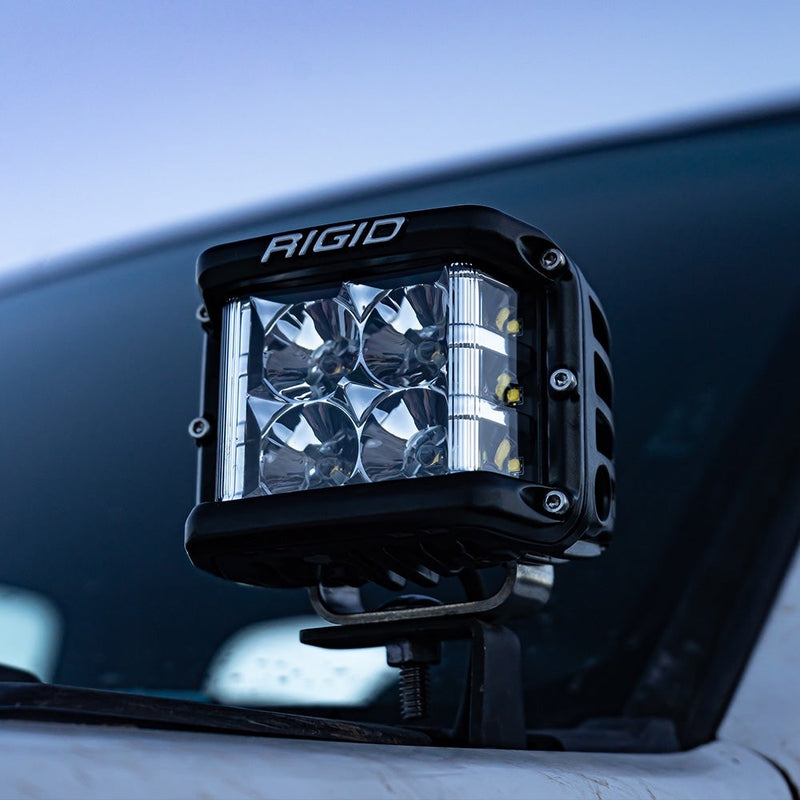 Rigid D-SS PRO Pods Pair installed on a vehicle: A black D-SS PRO pod mounted on a cowl bracket at the base of a windshield