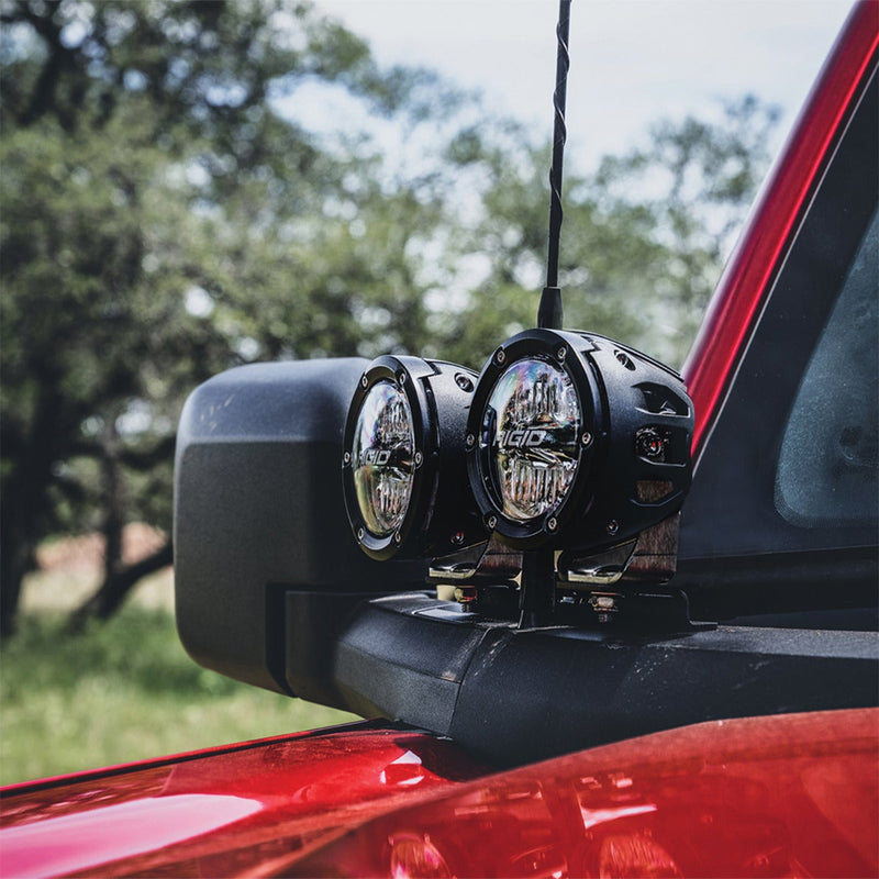 Rigid Dual Pod A-Pillar Mount Kit installed on a Ford Bronco: two round black pods on an A-pillar mount next to the side mirror of a red Ford Bronco under trees