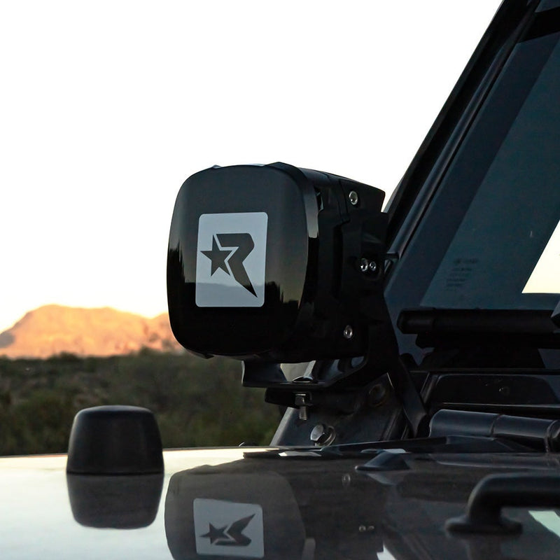 Rigid Phoenix Black Light Color installed on a vehicle: black Rigid R cover fitted to an A-pillar mounted pod on a dark vehicle at sunset