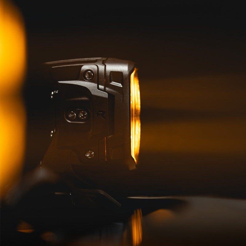 Close-up of the Rigid Phoenix Light Pod: side profile of a pod housing with an amber glow in a dark setting