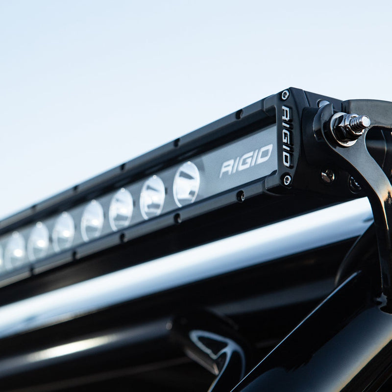 Close-up of the Rigid Radiance+ SR-Series 10" RGBW: close-up of a black Rigid SR-Series light bar mounted on a roof rack against a pale sky