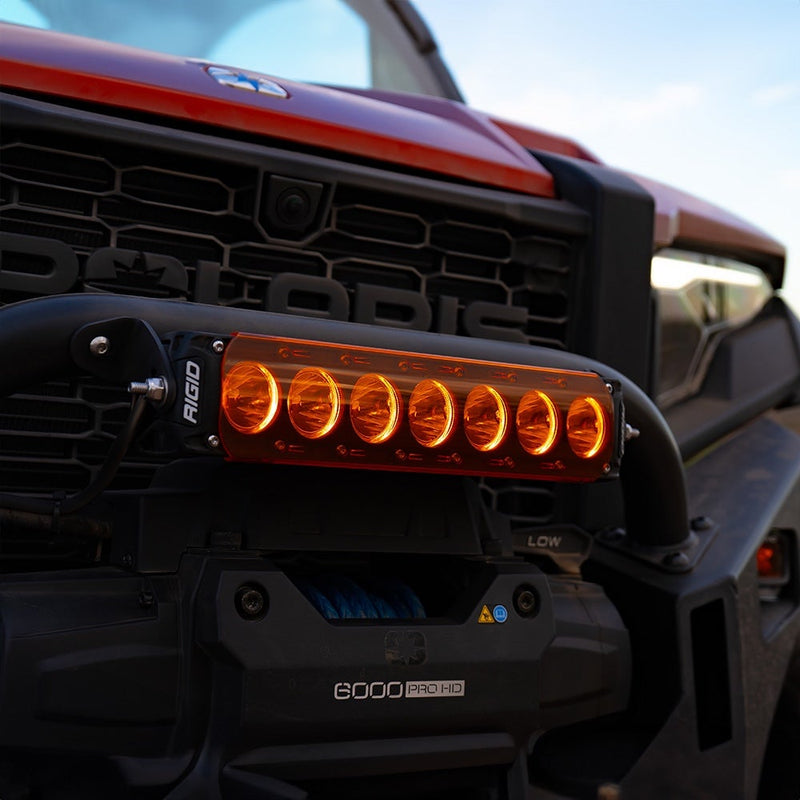 Rigid Revolve 10" Bar installed on a Polaris Polaris XPEDITION: A short Revolve light bar glowing amber, mounted on the front bumper of a Polaris side-by-side under the POLARIS grille lettering