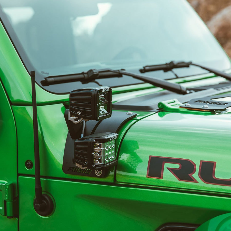 Vehicle-Specific Mounts & Brackets by Rigid: Two Rigid D-Series pods sit on a cowl mount at the windshield of a green Jeep.