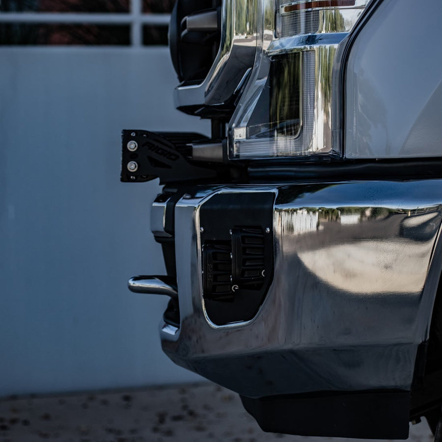 Vehicle-Specific Mounts & Brackets by Rigid: Close view of a black bar mount bracket fitted behind the corner of a chrome front bumper.