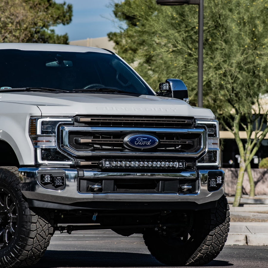 Vehicle-Specific Mounts & Brackets by Rigid: Front three-quarter view of a white Ford Super Duty with a light bar mounted in the bumper.