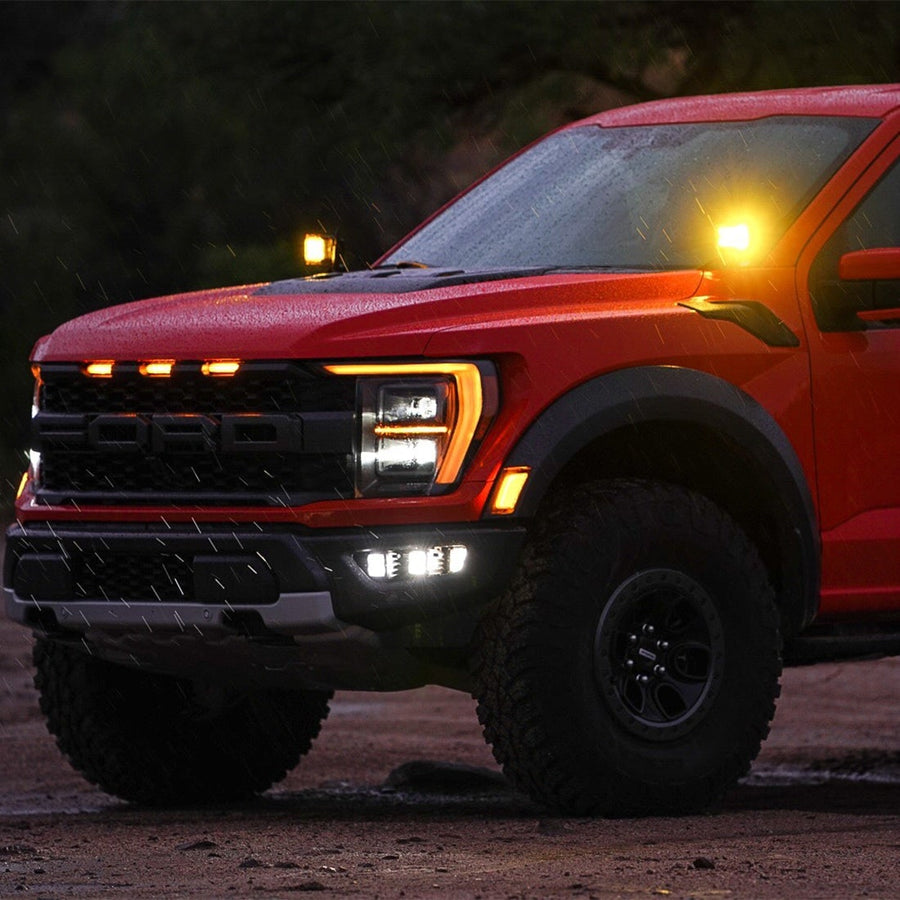 Vehicle-Specific Mounts & Brackets by Rigid: A red Ford Raptor at dusk with amber lit pods on both A-pillars.